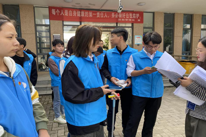 图为卢老师给志愿者学生分配任务.png