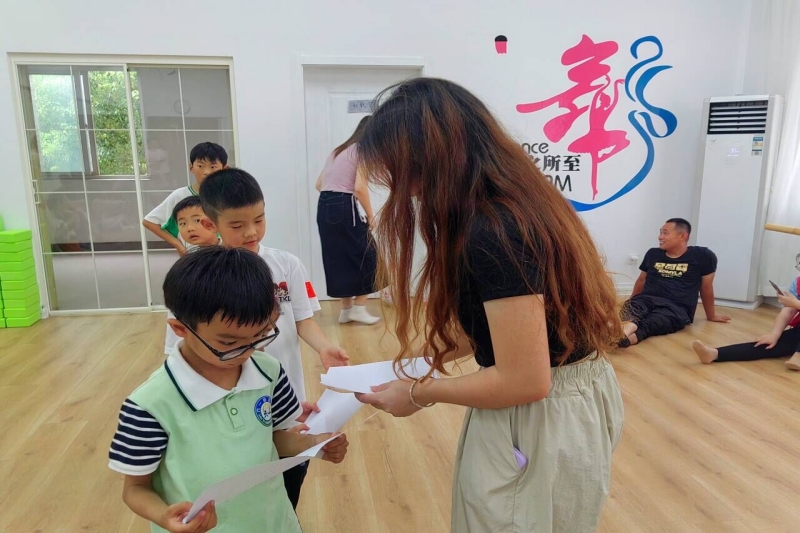 图为实践团成员为小朋友们分发画纸.jpg