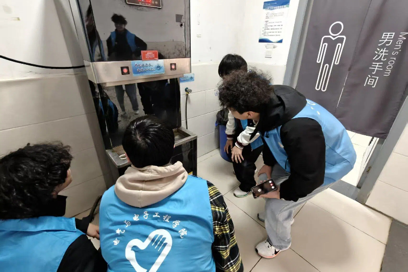 图为志愿者排查教学楼饮水机问题.jpg