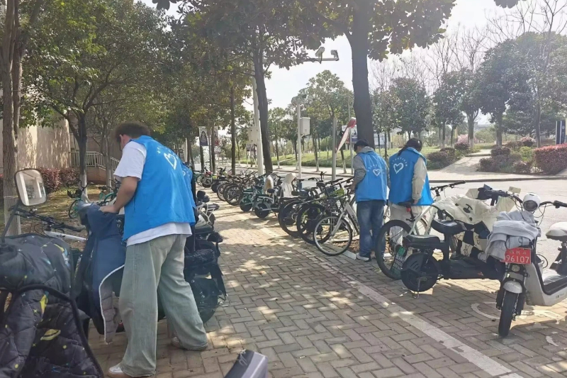 图为志愿者对单车摆放整齐.jpg