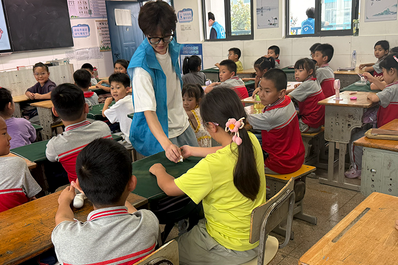 图为实践队员为小学生发放礼品.png